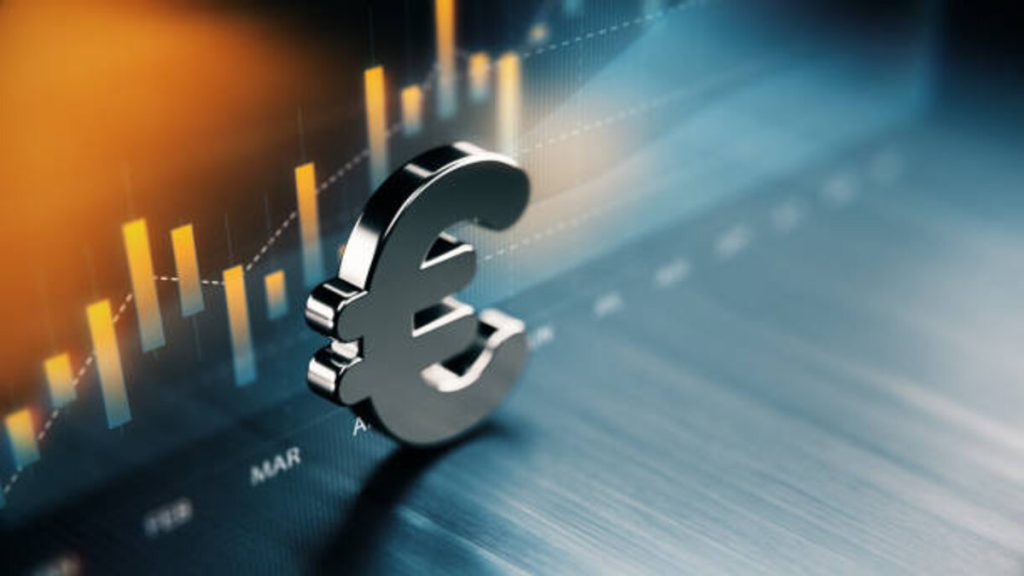 european union currency symbol standing on wood surface in front of a graph